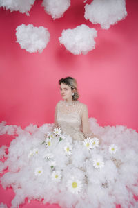 Portrait of woman with pink flowers against red wall