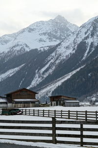 Snow covered houses by mountain against sky