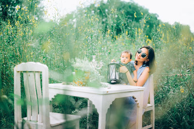 Woman sitting on table against plants