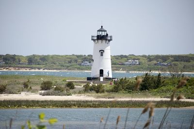 Lighthouse by sea against clear sky