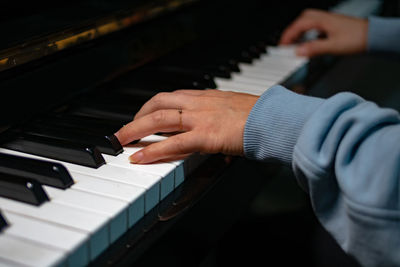 Cropped hands of woman playing piano