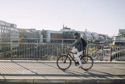 Businessman riding bicycle on cycling path against buildings in city