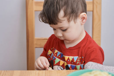 Cute boy is playing with his pasta at lunch time