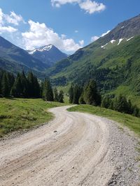 Scenic view of road by mountains against sky