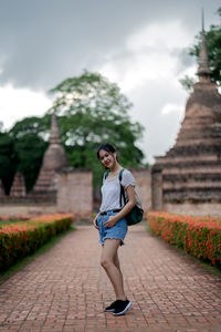 Full length portrait of young woman standing outside temple