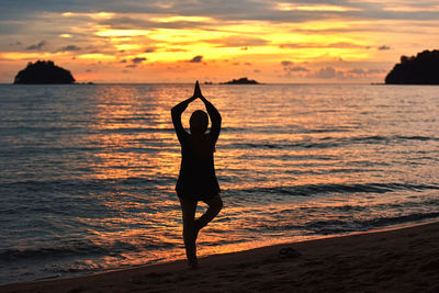 Silhouette woman on beach against sky during sunset