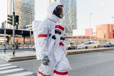 Mid adult astronaut crossing street in city
