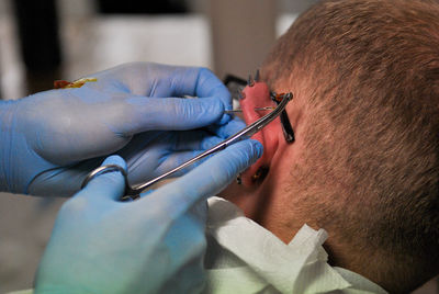 Cropped hands piercing man ear