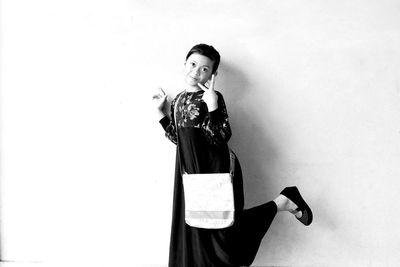 Portrait of young woman smoking against white background