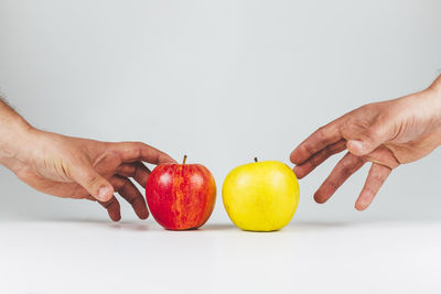Cropped image of hand holding apple against white background