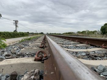 Railroad tracks by electricity pylon against sky