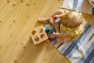 High angle view of baby girl sitting on hardwood floor at home