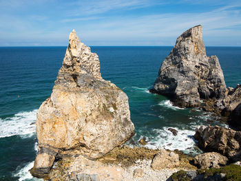 Rock formation on sea shore against sky