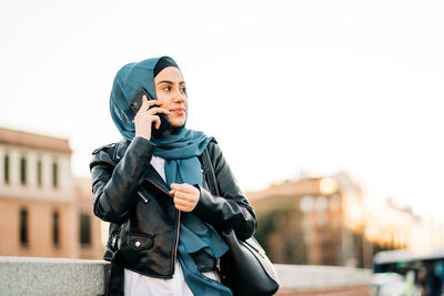 Portrait of young woman standing against the sky