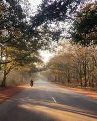 Man riding motorcycle on road in city against sky