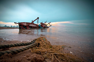 Abandoned boat in sea against sky