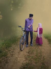 Rear view of couple walking on bicycle