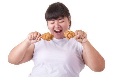 Young woman eating fried chicken meat against white background