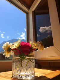 Flower vase on glass table against window