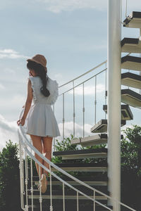 Woman standing by railing against sky