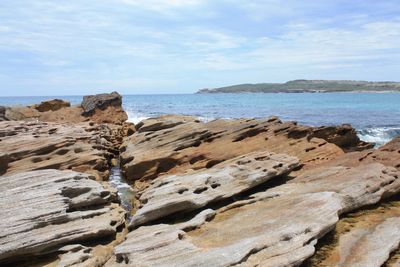 Scenic view of cliff by sea against sky