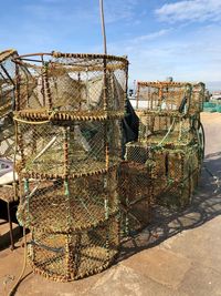 Stack of fishing net at harbor against sky