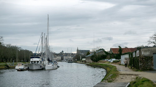 Sailboats in river by buildings in city against sky