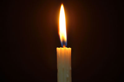 Close-up of lit candle against black background