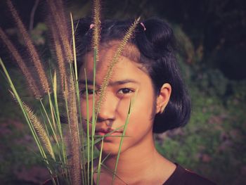 Close-up portrait of serious girl holding plants