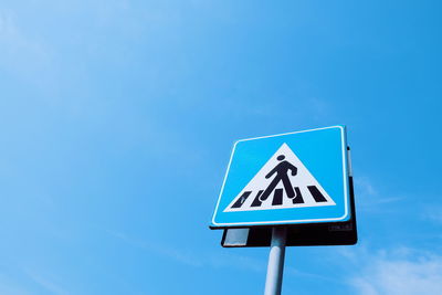 Low angle view of road sign against blue sky