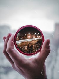 Close-up of hand holding glass against sky