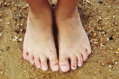 Low section of woman standing on sand at beach