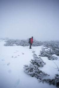 Person on snow covered mountain against clear sky