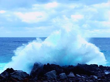 Panoramic shot of waves breaking against rocks