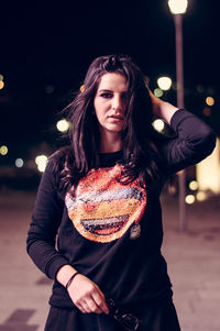 Portrait of young woman standing outdoors at night