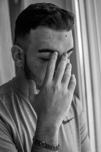 Sad young man sitting by window at home