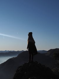 Man standing on rock against sky