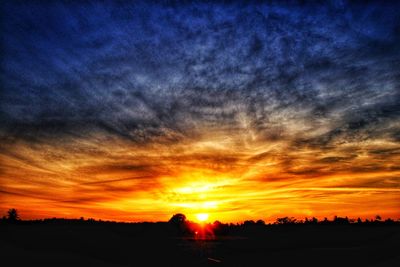 Silhouette landscape against dramatic sky during sunset