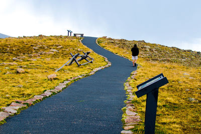 Rear view full length of man walking on footpath at hill