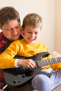 Father with son playing guitar while relaxing at home