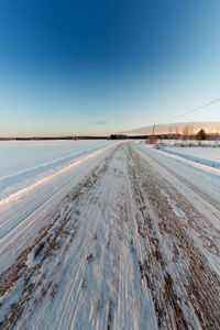 Snow covered land against clear blue sky