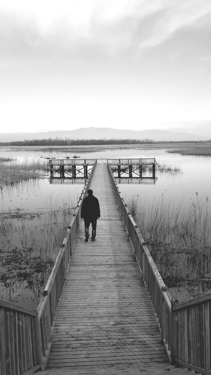 water, sea, sky, pier, horizon over water, the way forward, walking, men, rear view, lifestyles, tranquil scene, tranquility, leisure activity, railing, nature, scenics, full length, person, beach