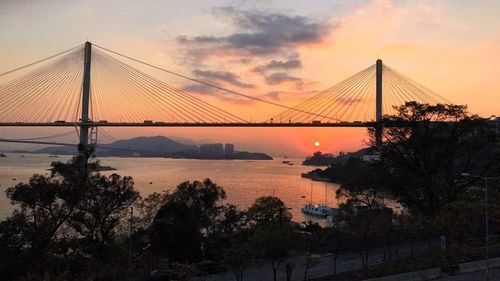 Silhouette of suspension bridge over lake during sunset