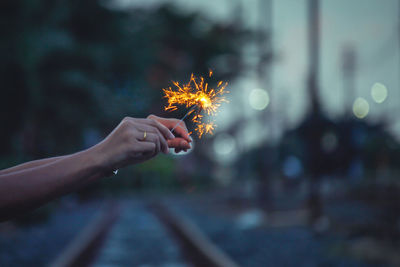 Midsection of woman holding sparkler at night