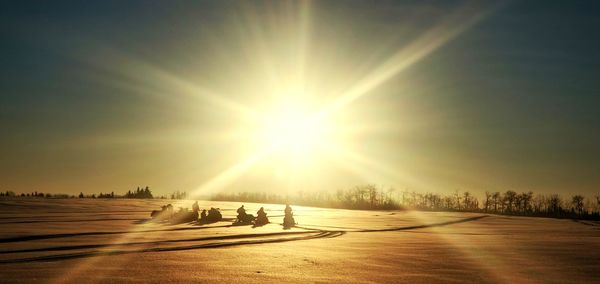People on snow covered landscape against bright sun