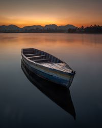 Boat moored on sea against sky during sunset