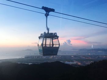 Overhead cable car over sea against sky during sunset