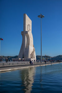 People at waterfront against clear blue sky
