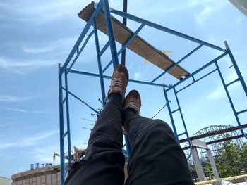 Low section of man and woman standing on ladder against sky