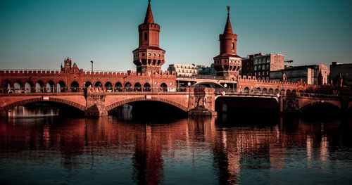 Bridge over river in city against clear sky